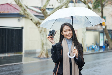 下雨天撑着伞的女性手拿照相机高清图片