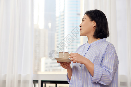中年女性窗前喝咖啡背景图片