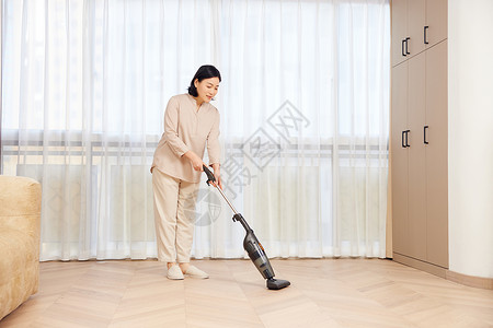 中年女性居家使用吸尘器背景图片