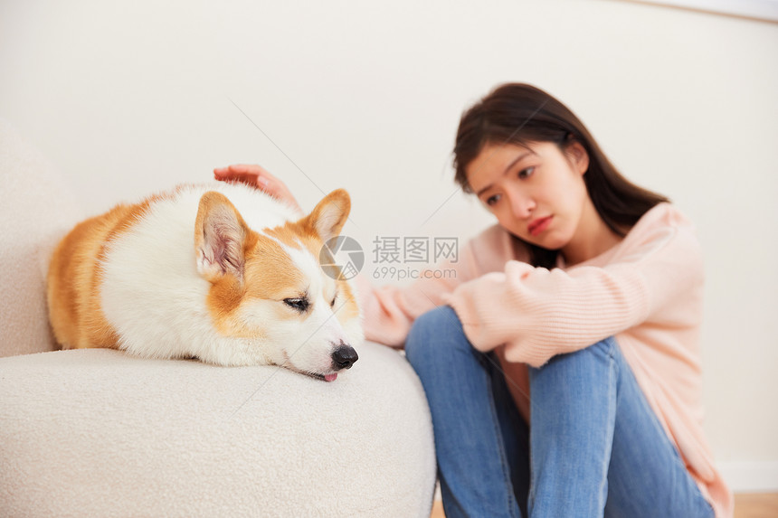坐在宠物狗旁边不开心的女性图片