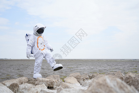 穿着宇航服的男性海边行走探索图片