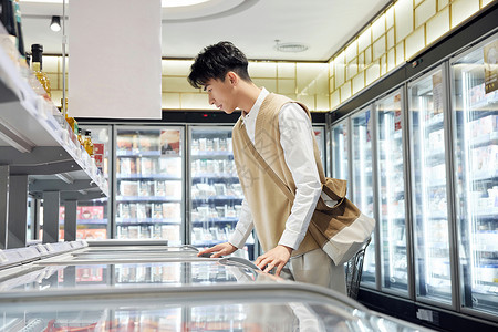 超市食品区前采购商品的青年男子图片