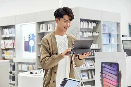 数码产品店体验平板电脑的青年男性高清图片