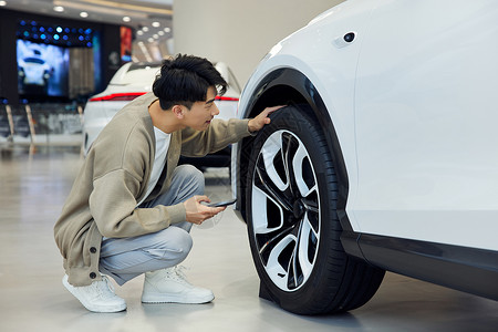 汽车4s店查看轮胎的青年男性高清图片