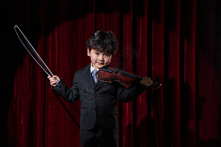小男孩舞台上演奏小提琴背景图片