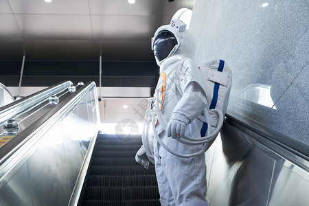 穿宇航员的男性乘坐地铁电梯背景图片