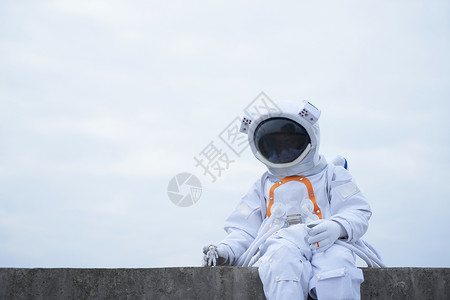 户外穿着太空服手拿宇航员模型的男性图片
