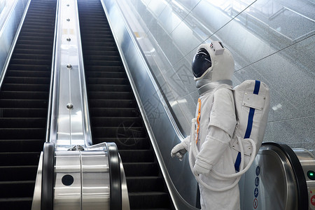 穿宇航员的男性乘坐地铁电梯形象图片