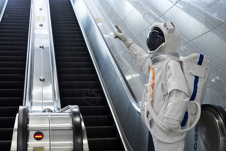 穿宇航员的男性乘坐地铁电梯图片