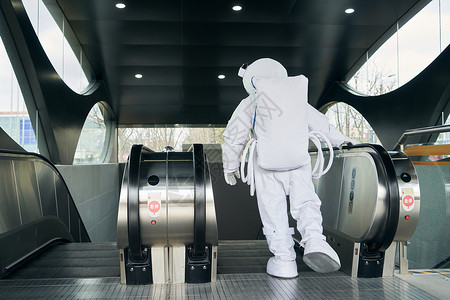 穿宇航服的男性乘坐地铁电梯背影图片