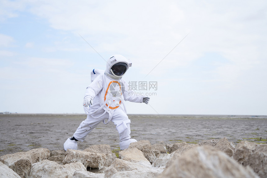 穿着宇航服的男性海滩边行走图片