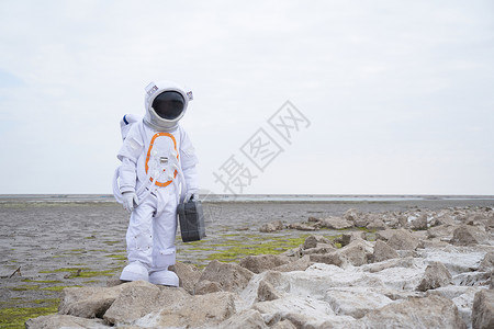 太空岩石穿着宇航服的男性拿手提箱背景