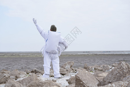 创意太空素材穿着宇航服的男性脱下帽子看远方背景