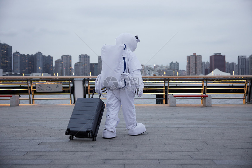 穿着宇航服的男性拖行李箱图片