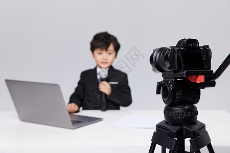 小孩相机镜头前手拿话筒的可爱小记者背景