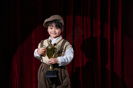 颁奖台素材舞台上手拿奖杯的小男孩背景