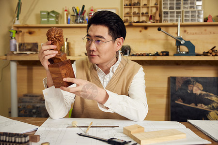 男性手艺人手拿木头雕刻图片