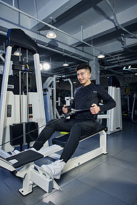 正在示范使用坐姿划船器的健身男教练健身房高清图片素材
