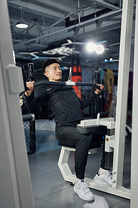 健身房进行高位下拉训练的健身男性背景