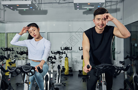 健身房动感单车激烈训练的运动情侣背景图片