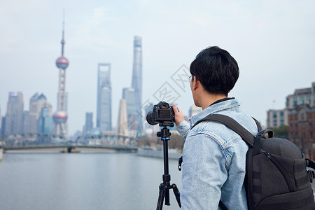 男摄影师使用三脚架拍摄城市风光照背景图片