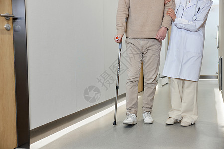 女医师搀扶腿伤病人走过走廊特写图片
