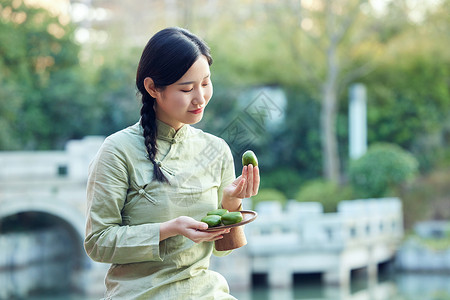 青年女性户外品尝青团背景图片