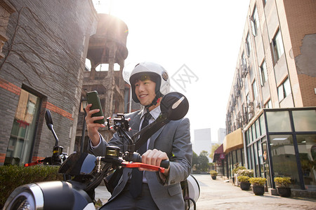 骑电瓶车的商务男青年使用手机背景图片