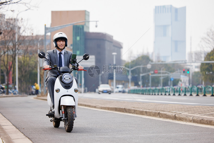 职场上班族骑着电瓶车行驶在车道上图片