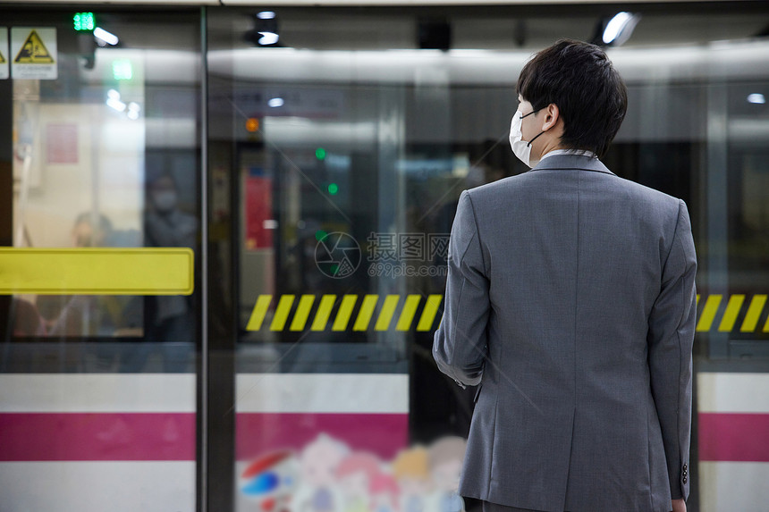 戴着口罩等待地铁的商务男性图片