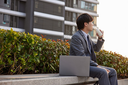 商务男性坐在室外喝水背景图片