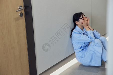 国际专家手写字崩溃地坐在医院走廊的护士背景