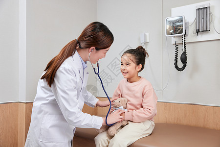 给小熊使用听诊器的小女孩和女医生背景图片