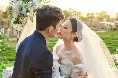 户外举行婚礼的新郎新娘甜蜜接吻背景图片