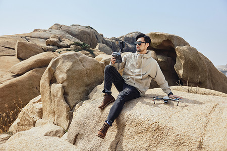 坐在山岩上的摄影师户外航拍摄影图片