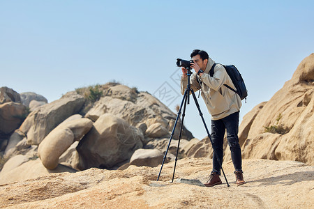 户外登山运动摄影师户外登山使用三脚架拍摄背景