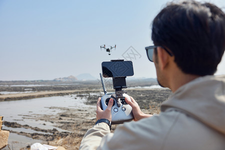 航拍摄影师户外操控无人机背影背景图片