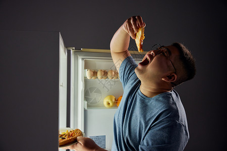 半夜肥胖男青年冰箱吃夜宵背景图片
