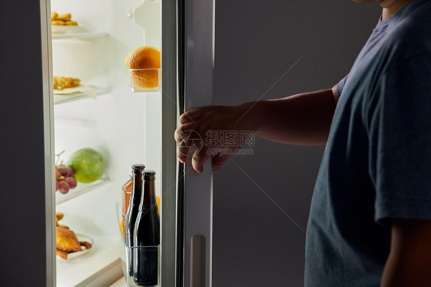 肥胖男士半夜开冰箱觅食特写图片