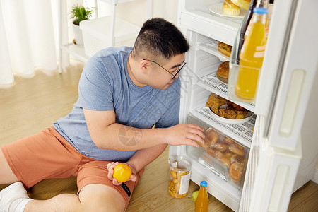 肥胖男士冰箱里翻找美食背景图片