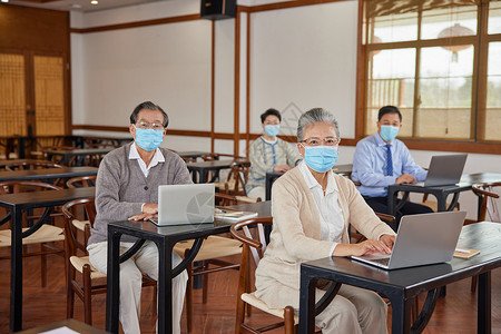 不聚会疫情在老年大学戴口罩使用电脑的老年人背景