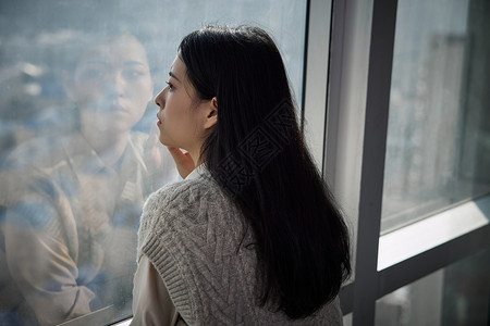 青年女性独自在家看向窗外图片