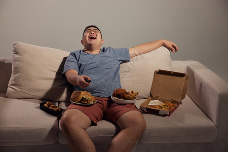 居家肥胖男青年看电视吃夜宵背景图片