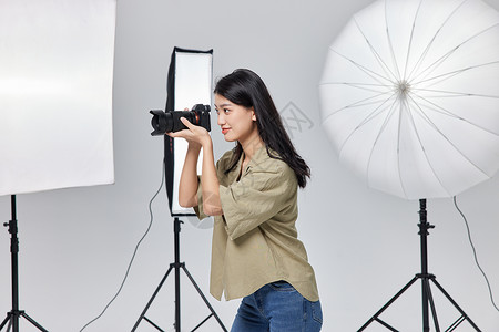商业女摄影师手拿相机拍摄照片单反高清图片素材