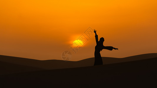 夕阳下沙漠山顶跳舞的女人剪影高清图片