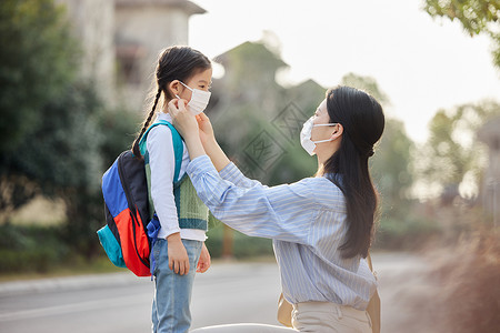 女儿放学素材室外妈妈帮女儿戴口罩背景