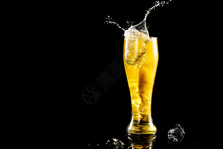 玻璃杯黄色啤酒冰块掉落在啤酒杯里溅起水花背景