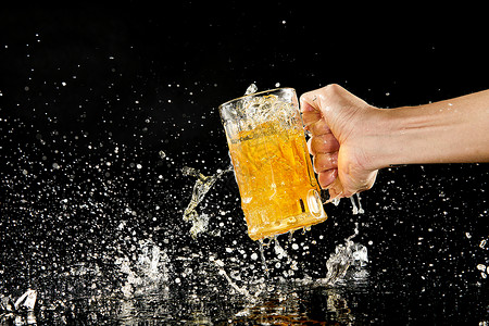 倒进玻璃杯手拿起放在桌面上的冰镇啤酒背景
