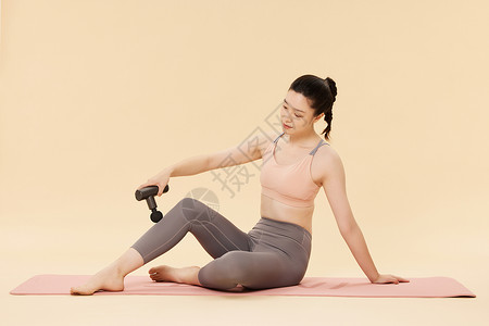 健身女性使用筋膜枪放松身体背景图片