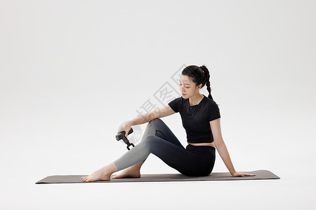 健身女性使用筋膜枪放松腿部肌肉背景图片